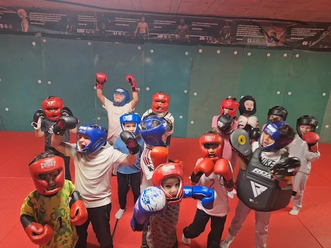 Le groupe des enfants du club, en casques et gants, lève les poings